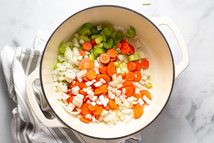 Large white pot with sliced carrots celery and onion 