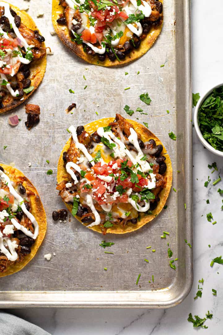 Overhead shot of a corner of a baking sheet with bbq chicken tostadas on it