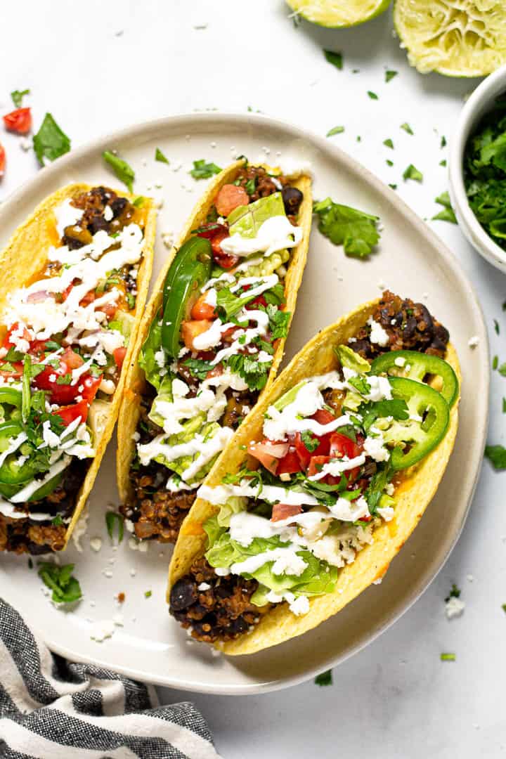 Overhead shot of a white plate filled with baked black tacos garnished with fresh cilantro 