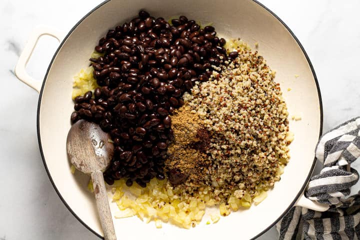 Large white pan filled with sauteed onion quinoa black beans and spices