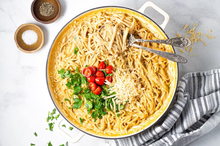 A large pot filled with fettuccine alfredo garnished with fresh parsley