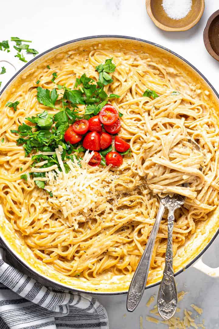 Overhead shot of a large pot filled with fettuccine alfredo garnished with fresh parsley