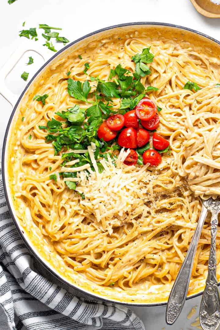 Overhead shot of a large pot filled with fettuccine alfredo garnished with fresh parsley