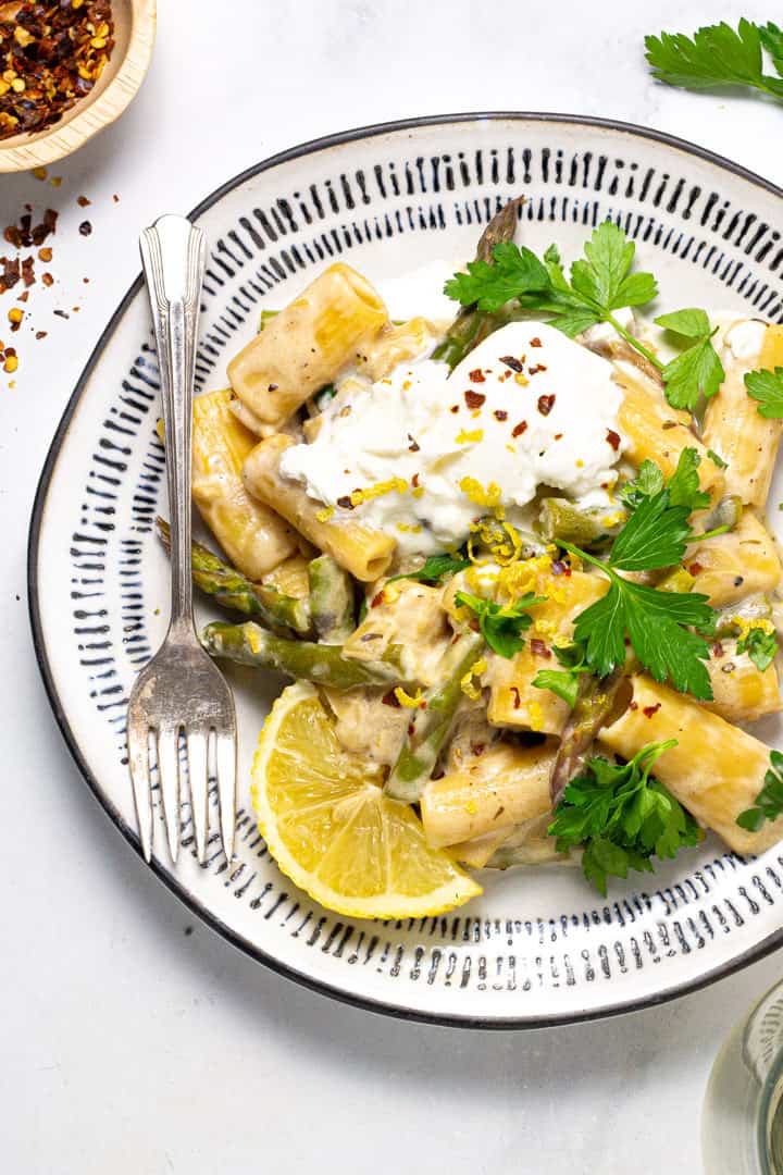 Black and white plate with lemon rigatoni garnished with fresh chopped parsley