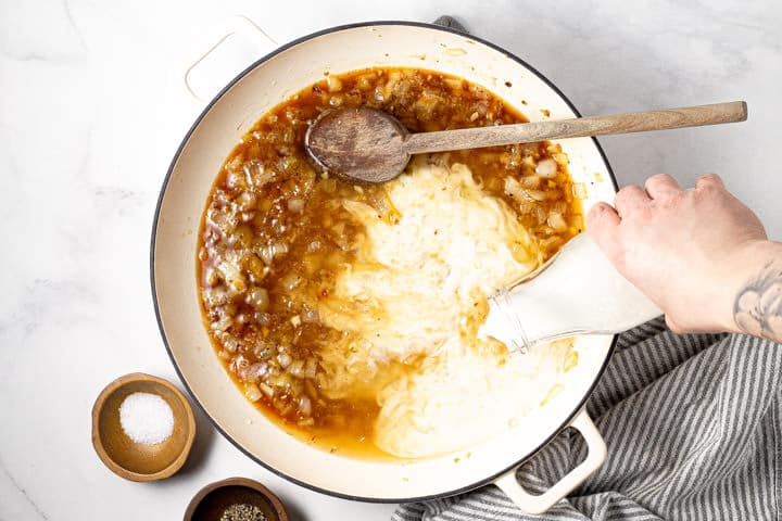 Half and half being poured into a pot of pasta sauce
