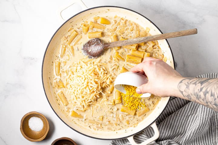 Lemon zest and Parmesan being added to a pot of rigatoni