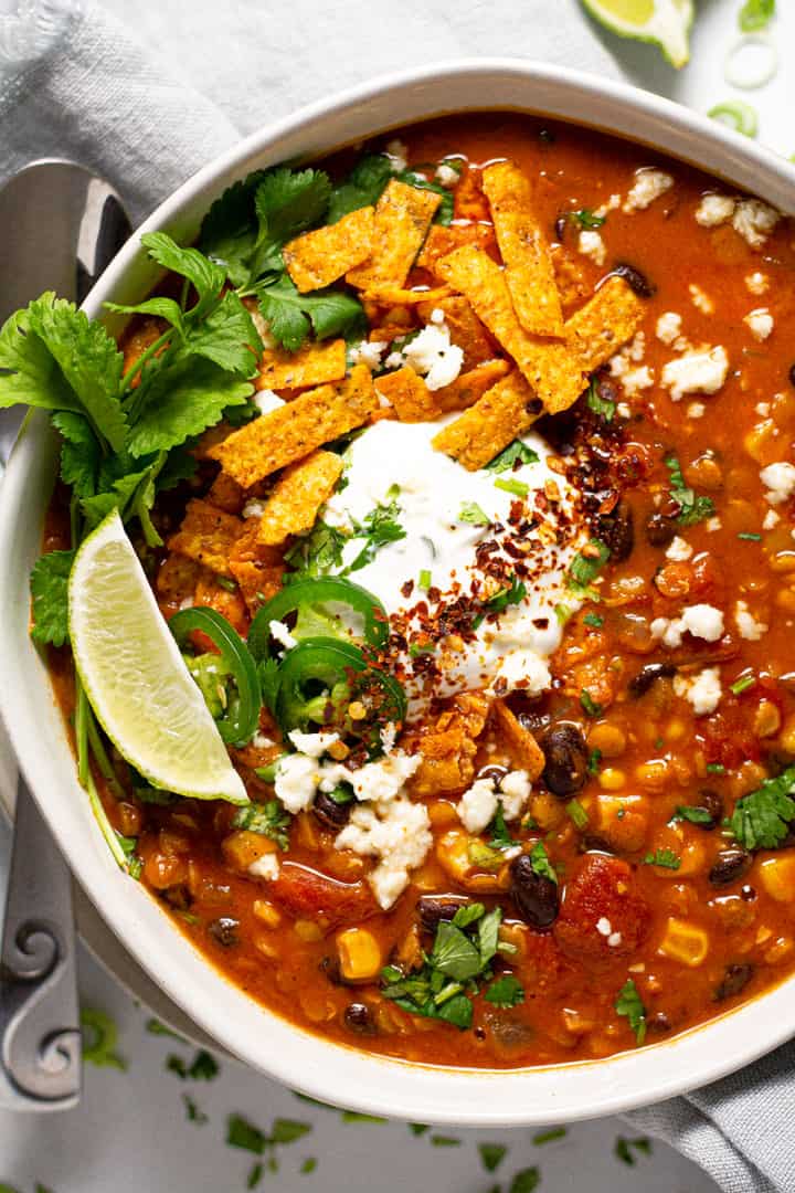 Overhead shot of a bowl of vegan lentil tortilla soup garnished with fresh chopped cilantro 