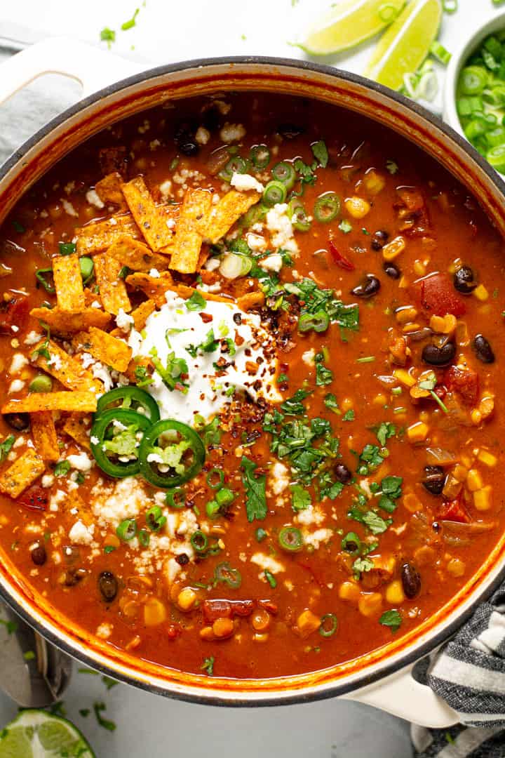 Overhead shot of a large pot of vegan lentil tortilla soup garnished with fresh chopped cilantro 