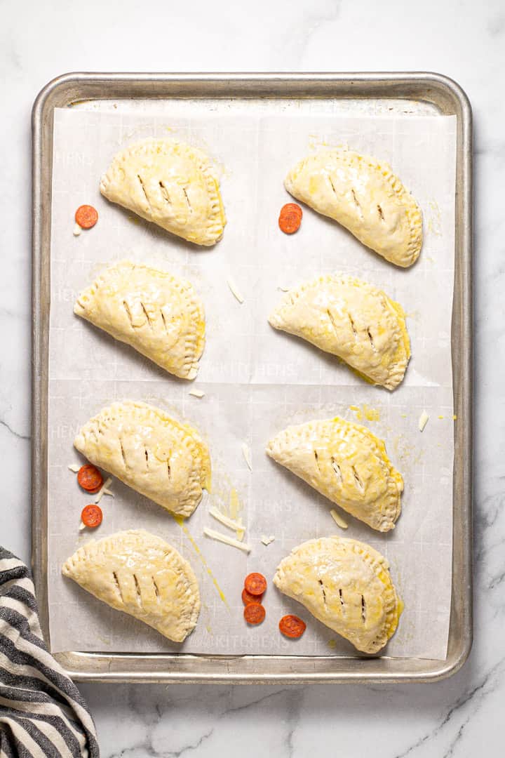 Unbaked calzones on a parchment lined baking sheet