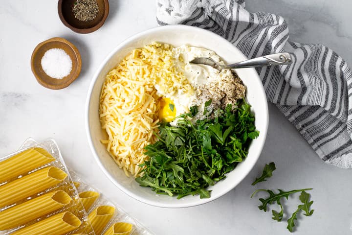 Large white bowl filled with ingredients to fill baked manicotti