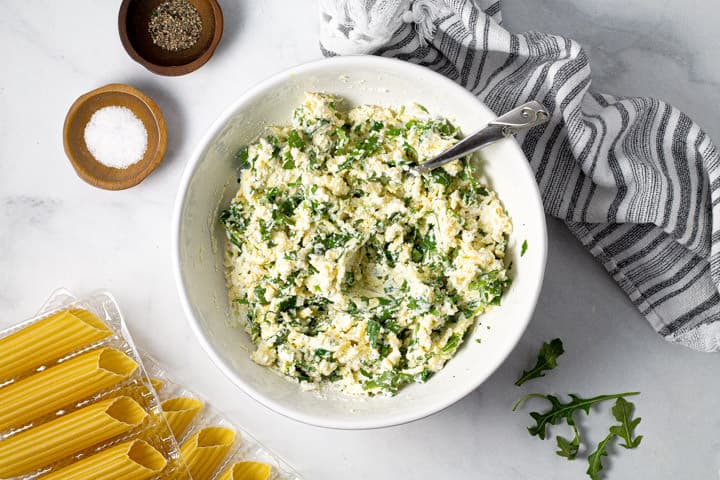 Large white bowl filled with ingredients to fill baked manicotti