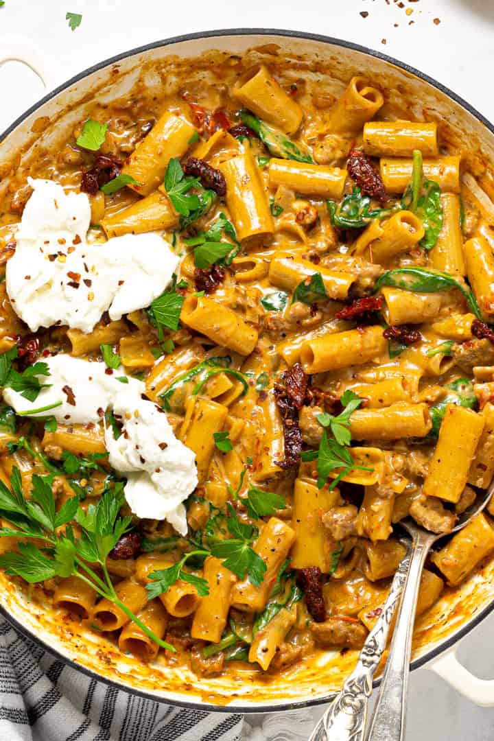 Overhead shot of a large white pot filled with one pot pasta garnished with fresh parsley