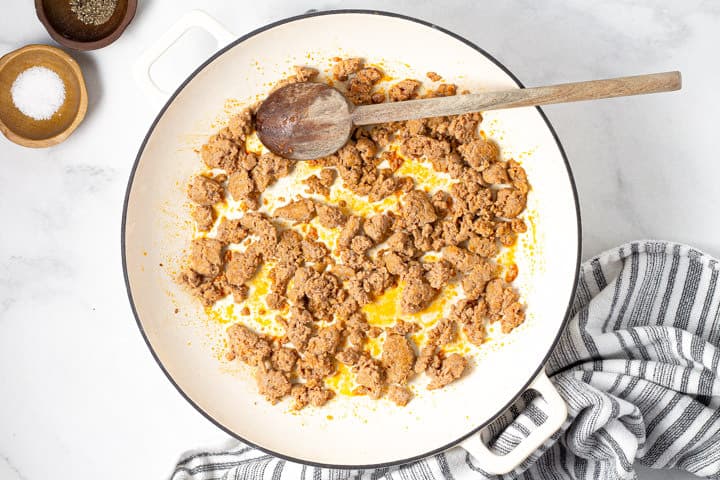 Large white pot with browned sausage in it
