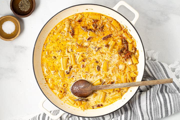 A large white pot with rigatoni and sauce in it