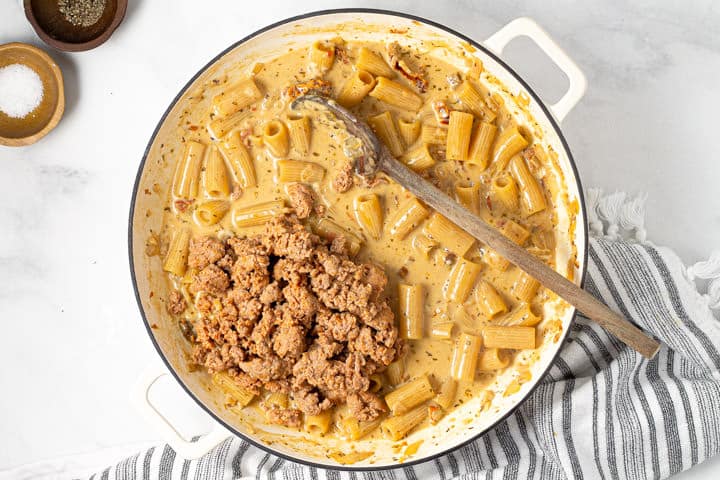 Browned sausage and cooked rigatoni in a large pot