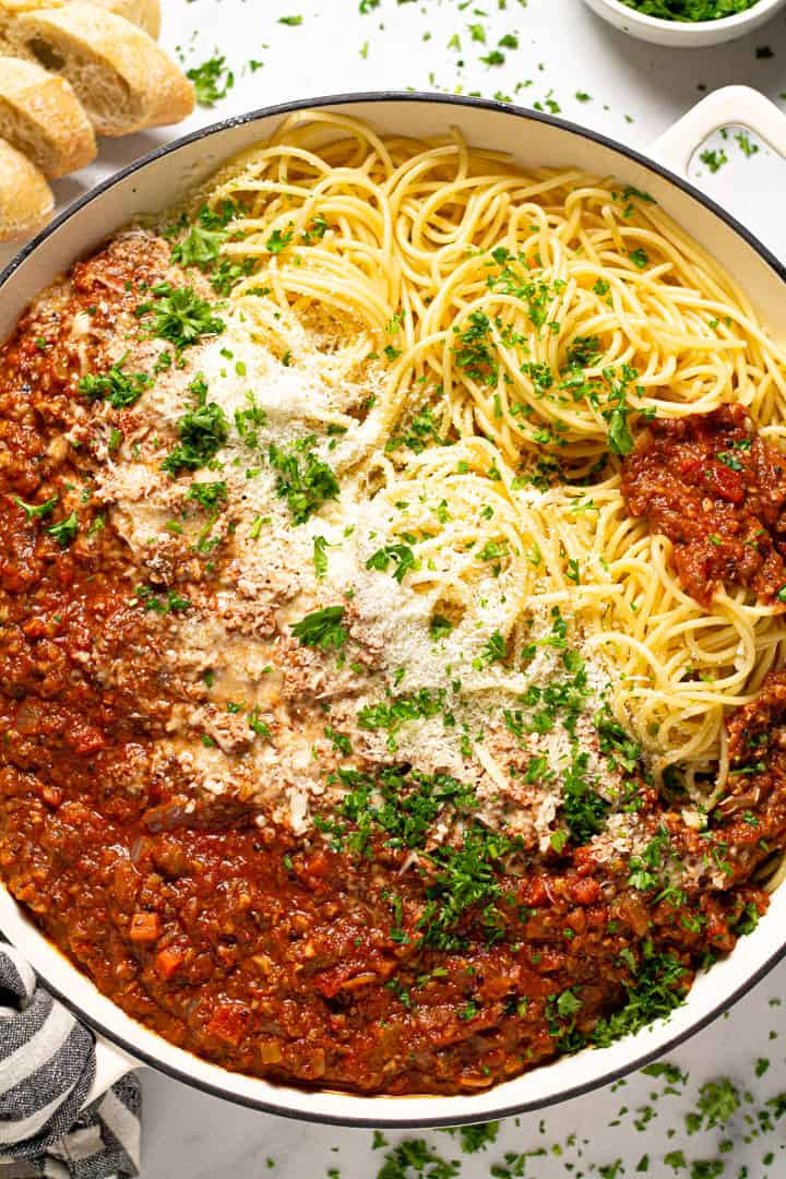 Overhead shot of a pan filled with spaghetti and vegetarian bolognese with fresh chopped parsley 