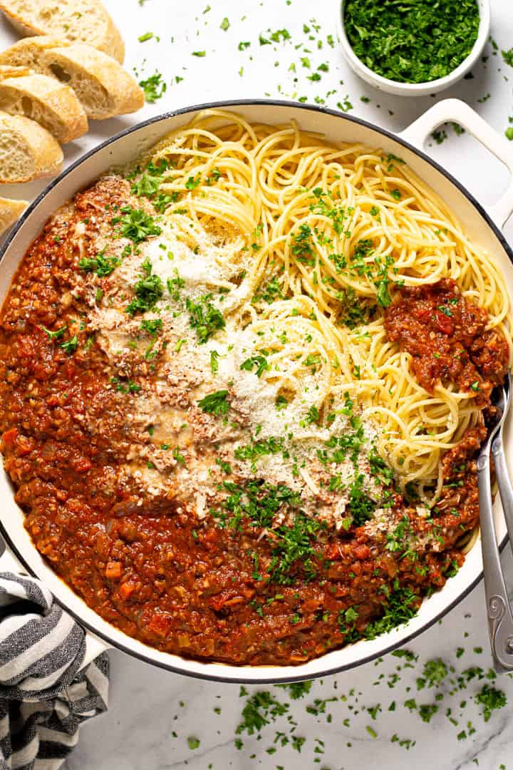 Overhead shot of a pan filled with spaghetti and vegetarian bolognese with fresh chopped parsley 