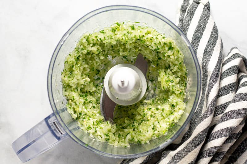 Overhead shot of a food processor with minced onion garlic and parsley in it