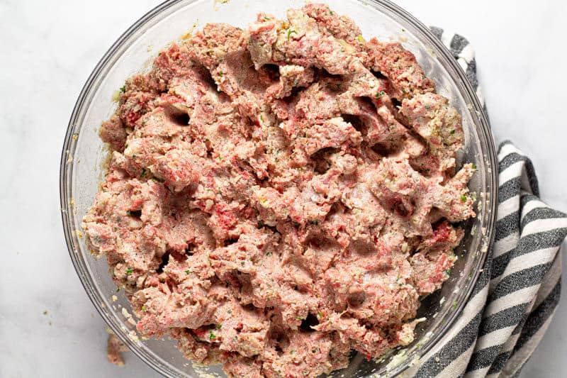 Large glass bowl filled with ingredients to make meatloaf