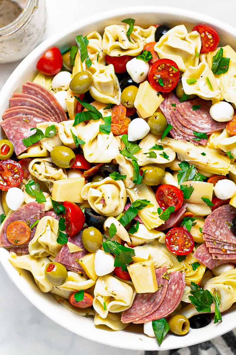 Overhead shot of a white bowl filled with antipasto pasta salad garnished with fresh parsley 