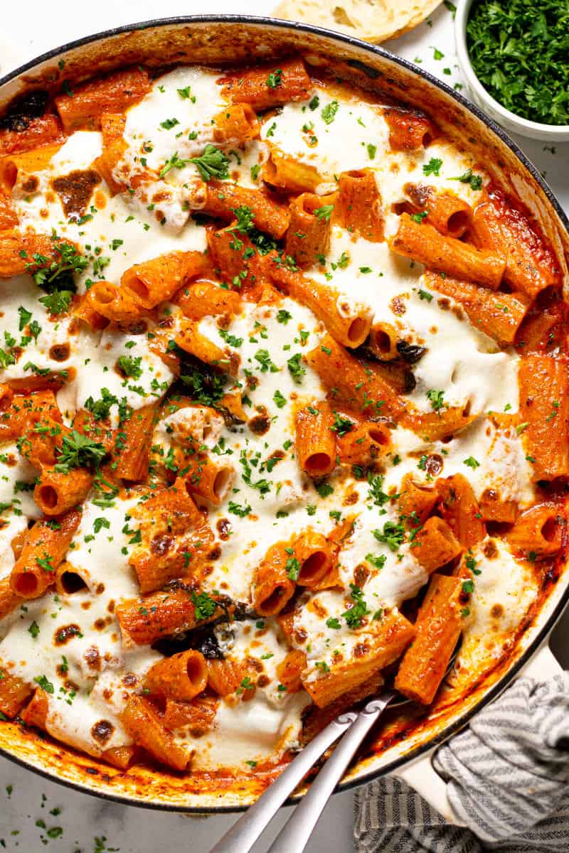 Overhead shot of a round baking dish filled with baked pasta garnished with fresh parsley