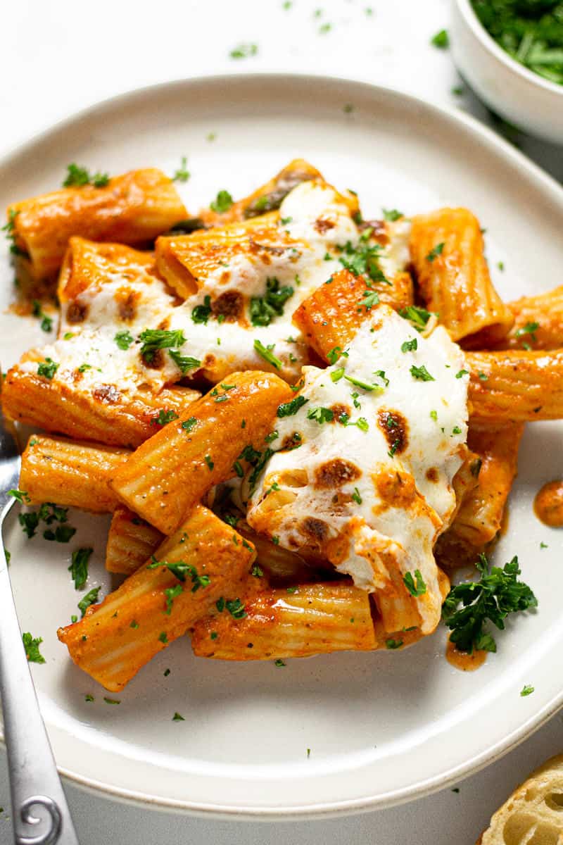 Close up shot of a plate of baked pasta garnished with fresh parsley