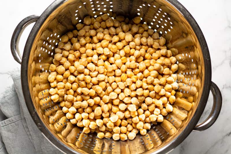 Silver metal strainer filled with soaked chickpeas 