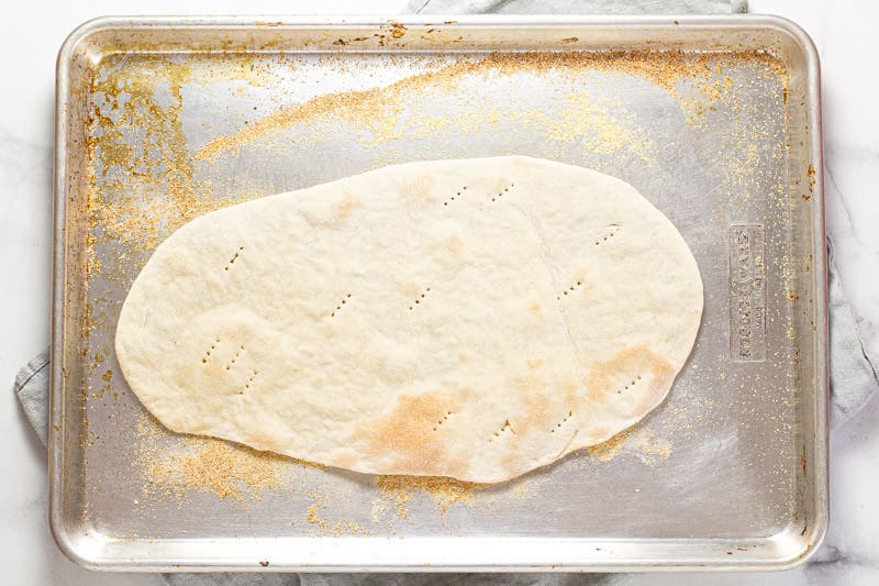 Flatbread dough on a cornmeal dusted baking sheet 