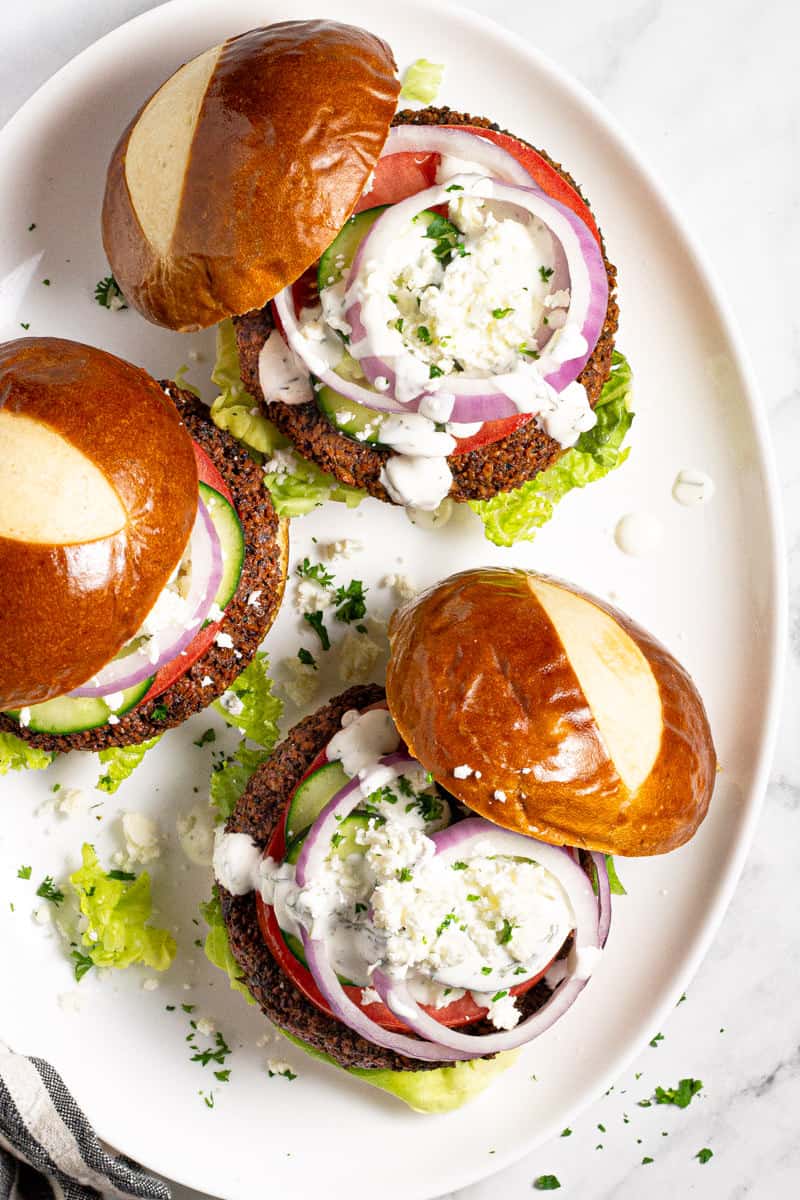 Large white platter with falafel burgers drizzled with yogurt sauce 