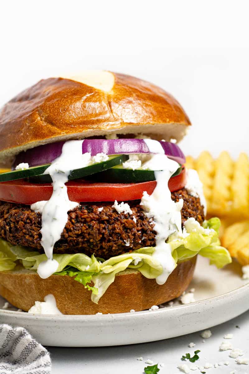 Close up shot of a falafel burger drizzled with dill yogurt sauce 