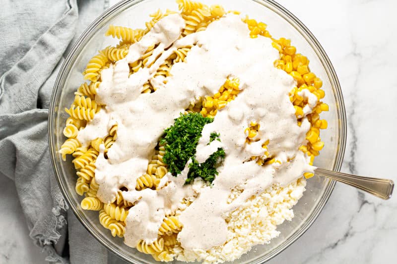 Large glass bowl filled with ingredients to make Mexican street corn pasta salad