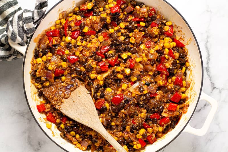 Large white pan filled with sauteed veggies corn black and quinoa
