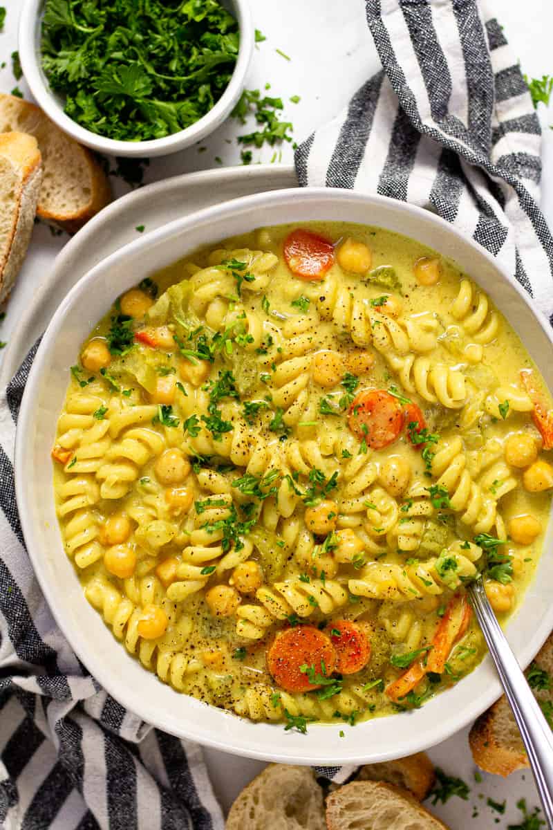 Overhead shot of a bowl of chickpea noodle soup garnished with chopped parsley 