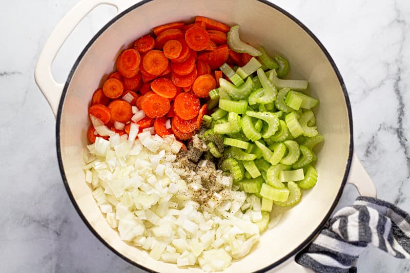 Large white pot filed with sliced carrots celery and onion