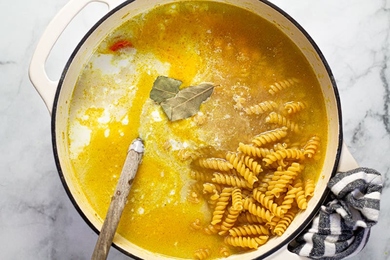 Large white pot filled with ingredients to make chickpea noodle soup 