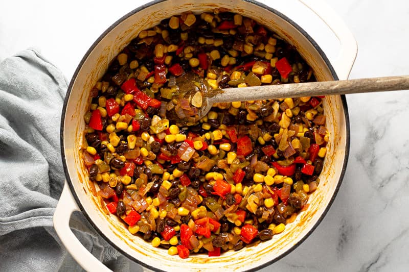 Large white pot filled with black beans corn and green chiles