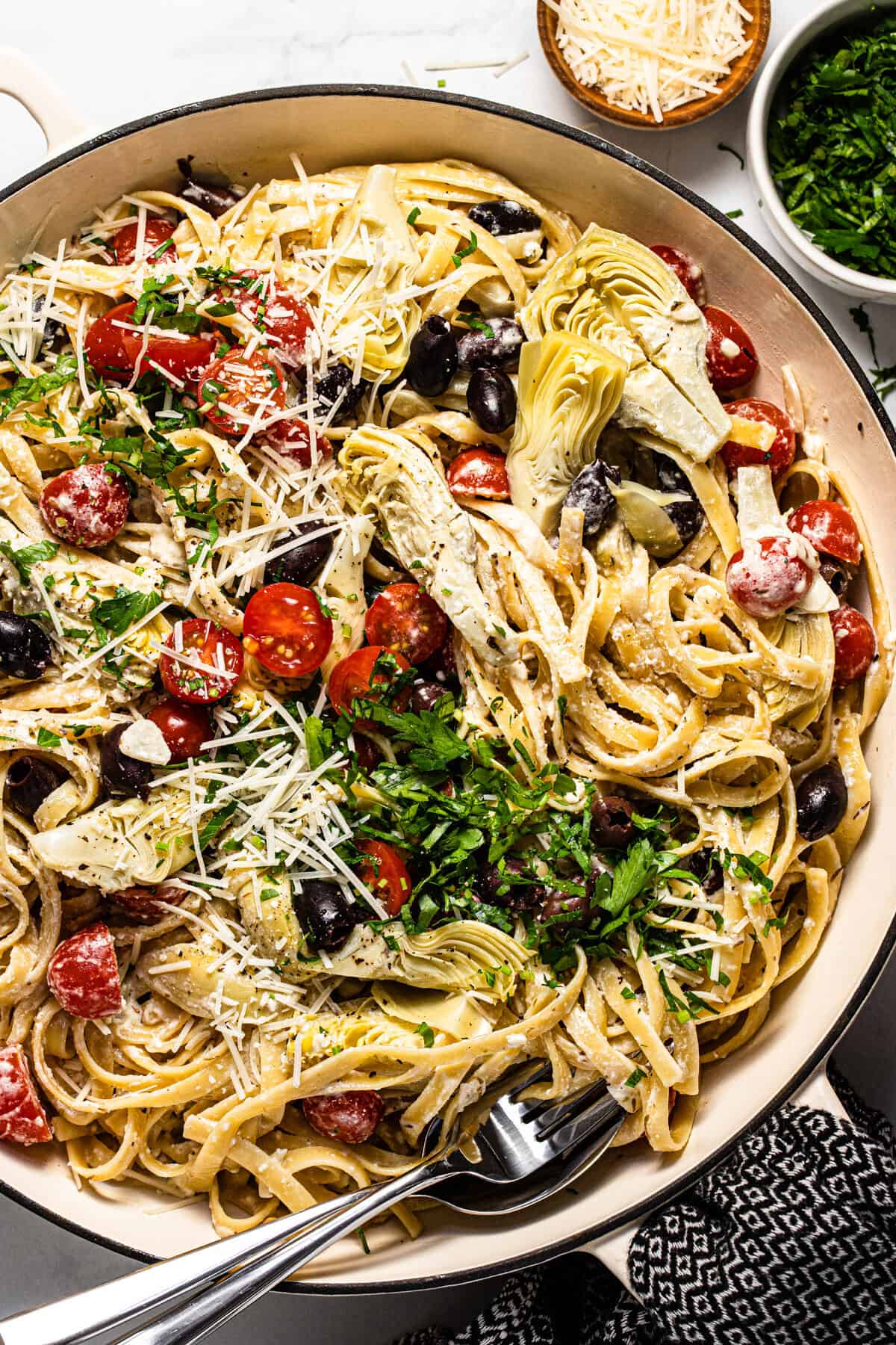 Large white pan filled with Greek pasta garnished with fresh chopped parsley