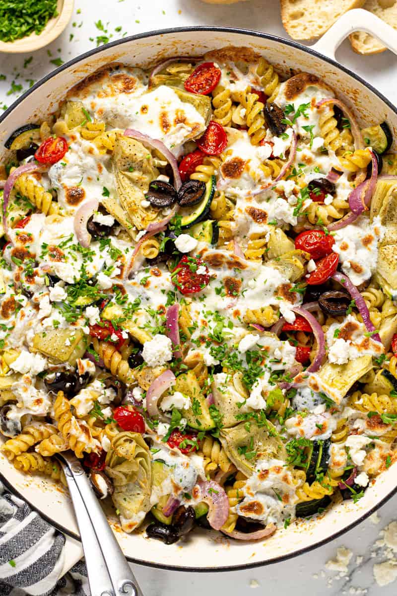 Overhead shot of a pan filled with baked Mediterranean pasta garnished with fresh parsley