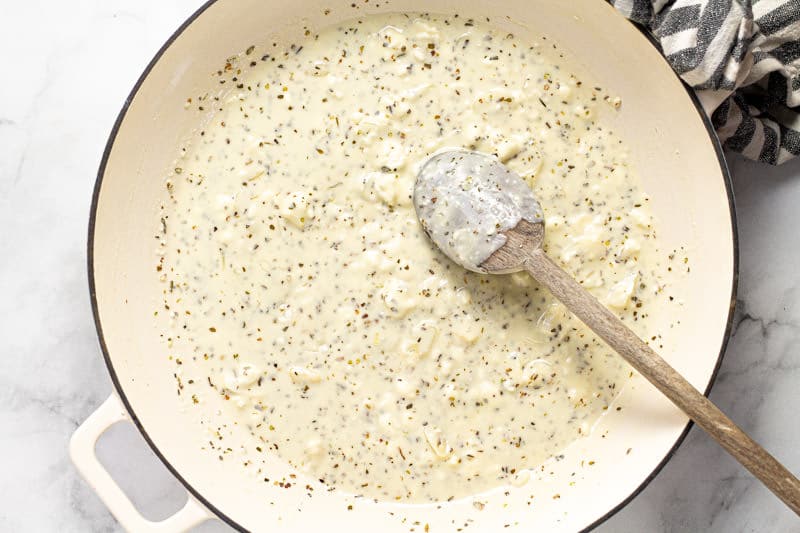 Large white pan filled with sauteed garlic dried oregano and feta sauce