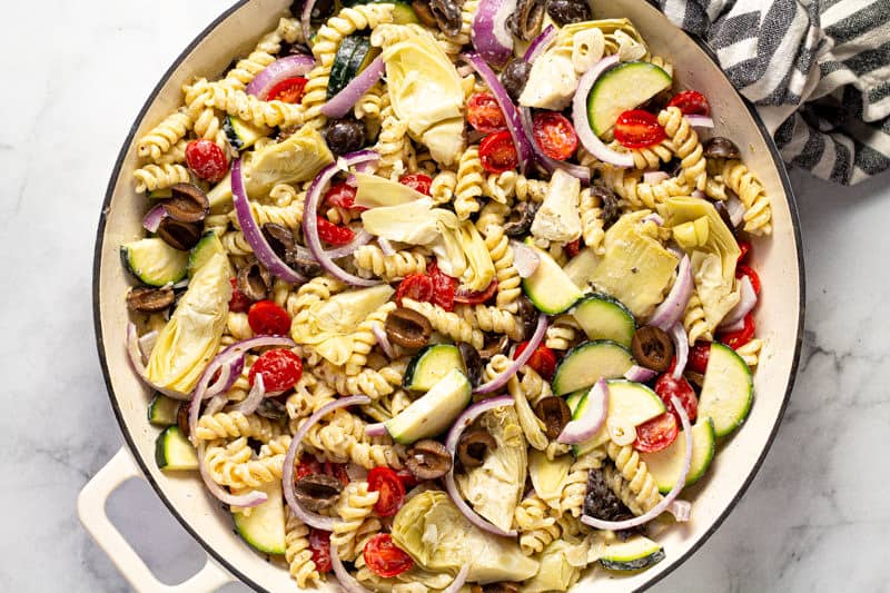 Zucchini olives red onion tomato and artichoke hearts mixed with pasta and feta sauce