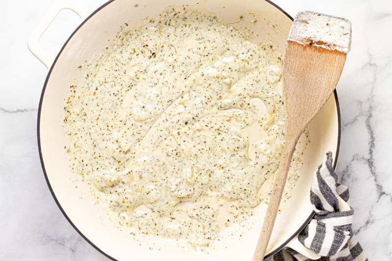 Large white pan with a creamy herb and garlic goat cheese sauce
