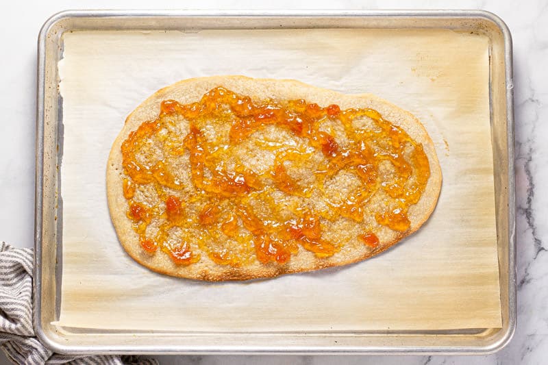 Baking sheet with a flatbread crust spread with apricot preserves