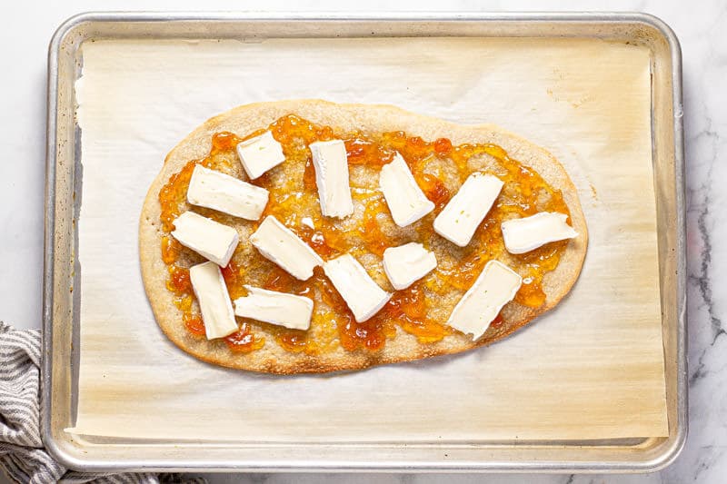 Baking sheet with a flatbread crust spread with apricot preserves and brie