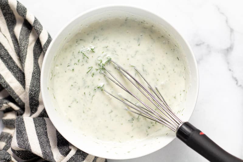Small white bowl with ingredients to make creamy cucumber salad dressing