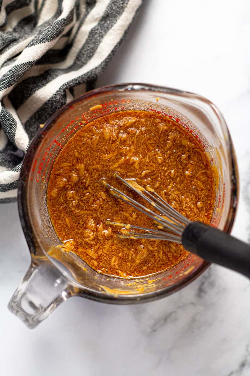 Overhead shot of a measuring cup with Thai peanut sauce being mixed together