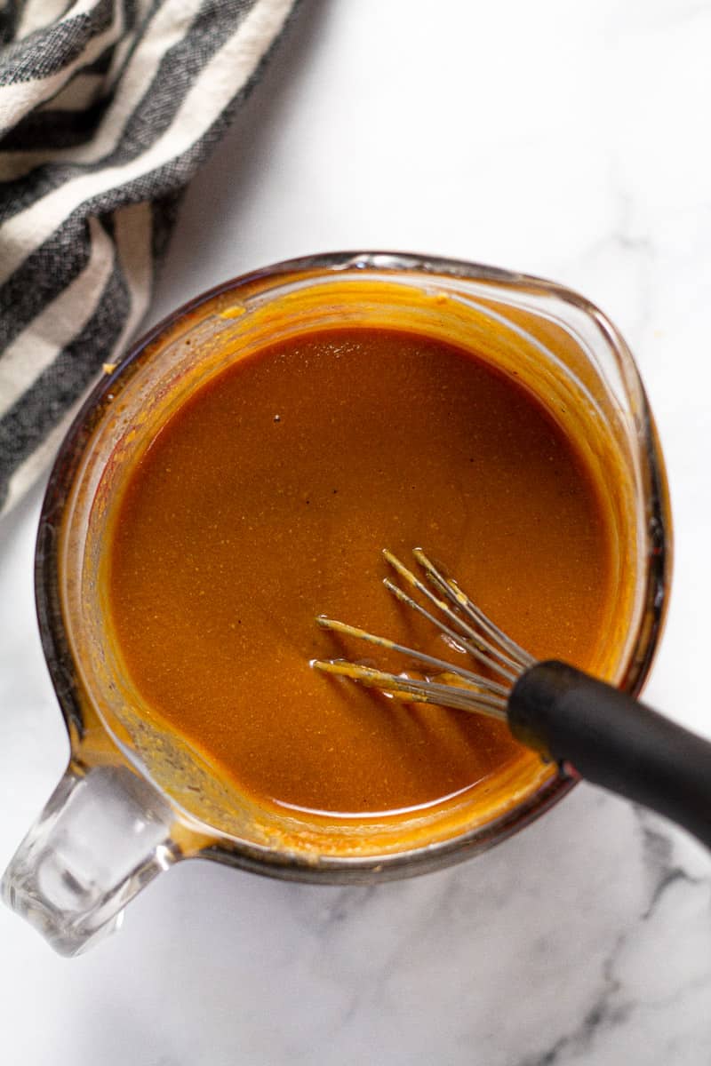 Overhead shot of a creamy Thai peanut sauce in a measuring cup