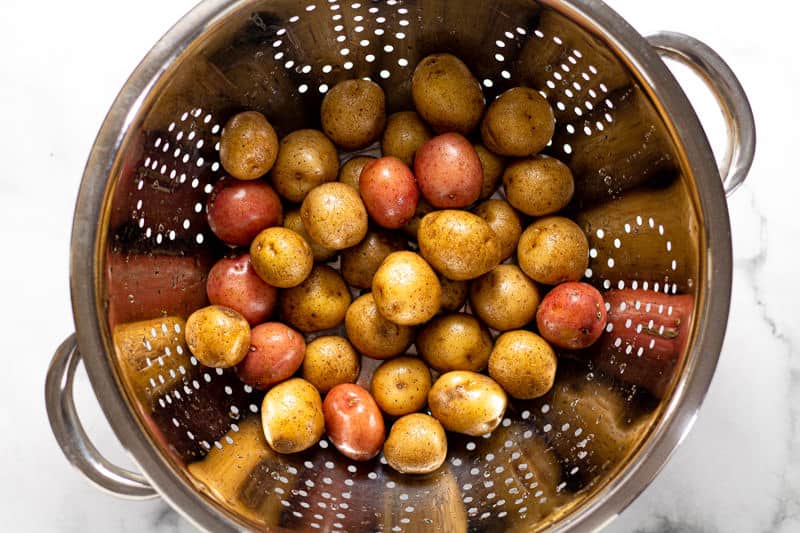 Metal strainer with baby gold and baby red potatoes in it 