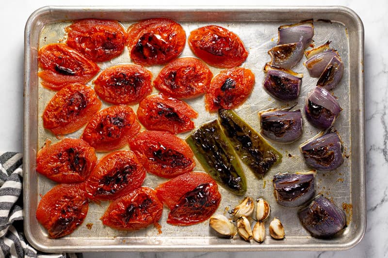 Baking sheet with broiled onions jalapeno and cloves of garlic on it