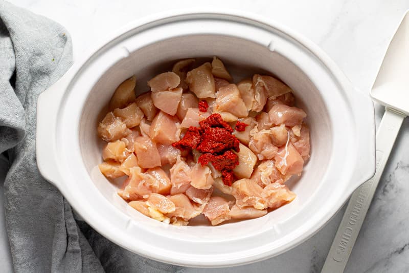 White oval bowl with diced chicken and curry paste