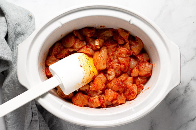 White oval bowl with diced chicken coated in curry paste
